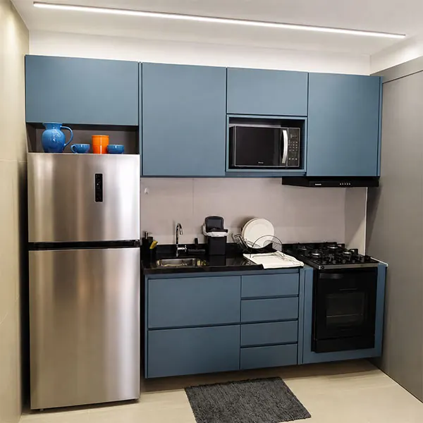 Cozinha compacta planejada em azul petróleo com forno, micro-ondas e gavetas sob medida